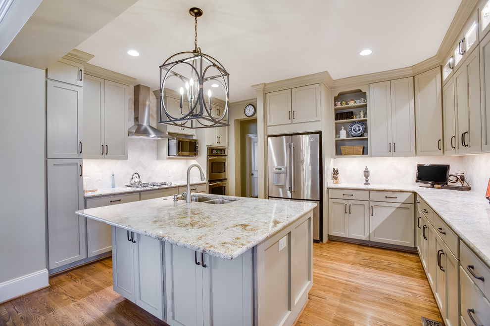 Enclosed kitchen - transitional u-shaped medium tone wood floor and brown floor enclosed kitchen idea in Birmingham with a double-bowl sink, shaker cabinets, beige cabinets, granite countertops, beige backsplash, travertine backsplash, stainless steel appliances and an island