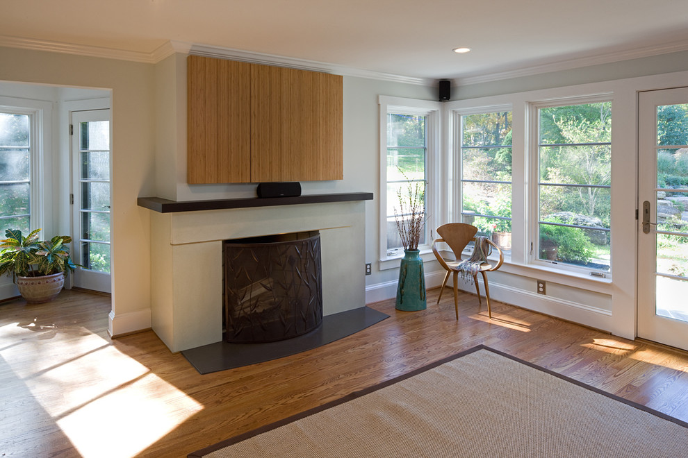 Mid-sized modern open concept family room in DC Metro with grey walls, light hardwood floors, a standard fireplace and a concrete fireplace surround.