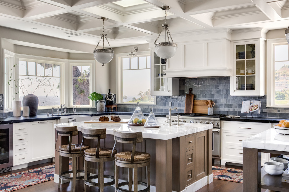 Design ideas for a transitional u-shaped kitchen in Orange County with a farmhouse sink, shaker cabinets, white cabinets, blue splashback, stainless steel appliances, dark hardwood floors, with island, brown floor and white benchtop.