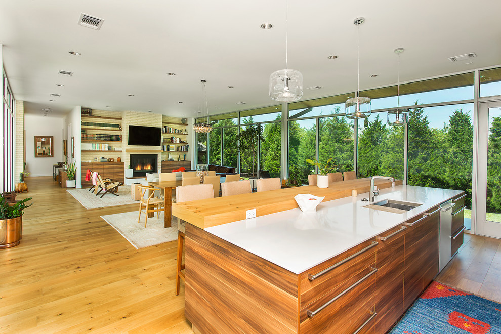 Inspiration for a mid-sized midcentury galley open plan kitchen in Dallas with an undermount sink, flat-panel cabinets, medium wood cabinets, quartz benchtops, beige splashback, brick splashback, stainless steel appliances, light hardwood floors, with island, beige floor and white benchtop.