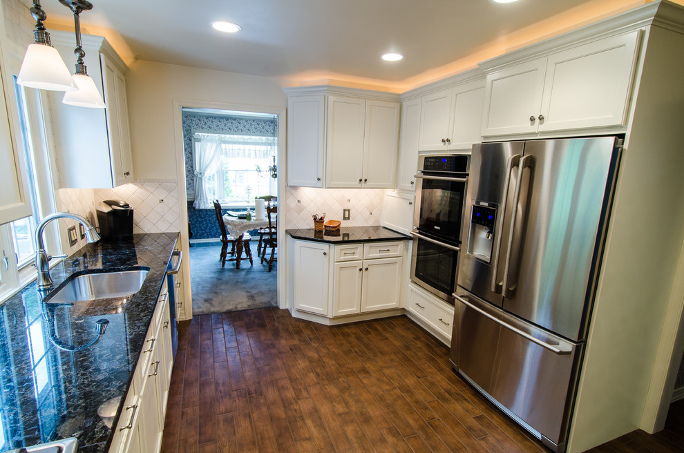 Mid-sized transitional l-shaped eat-in kitchen in Philadelphia with a single-bowl sink, white cabinets, granite benchtops, beige splashback, stone tile splashback, stainless steel appliances, porcelain floors, beaded inset cabinets and no island.