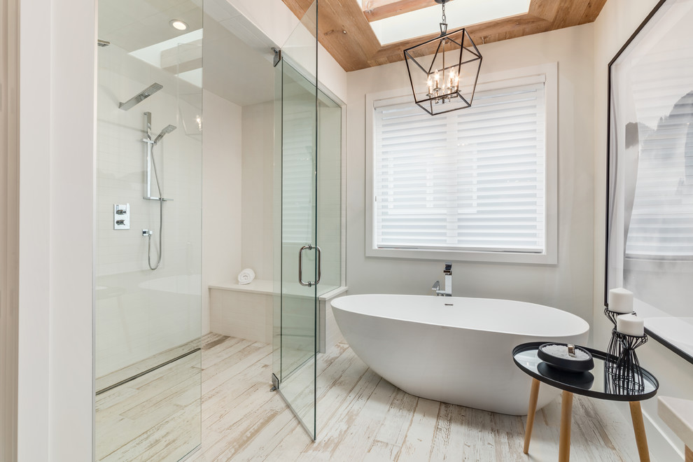 This is an example of a large contemporary master bathroom in Calgary with flat-panel cabinets, light wood cabinets, a freestanding tub, an alcove shower, white walls, light hardwood floors, an undermount sink, engineered quartz benchtops, white floor and a hinged shower door.