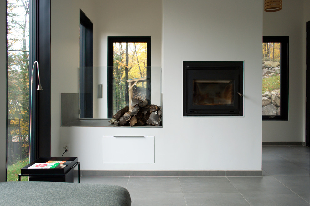 This is an example of a small scandinavian open concept living room in Montreal with white walls, ceramic floors, a standard fireplace, a plaster fireplace surround, no tv and grey floor.
