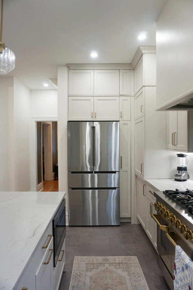 Example of a transitional vinyl floor and gray floor kitchen design with an undermount sink, shaker cabinets, gray cabinets, quartzite countertops, stone slab backsplash, stainless steel appliances and an island
