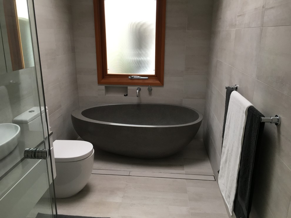 This is an example of a contemporary bathroom in Sydney with a freestanding tub, a corner shower, ceramic tile and a vessel sink.