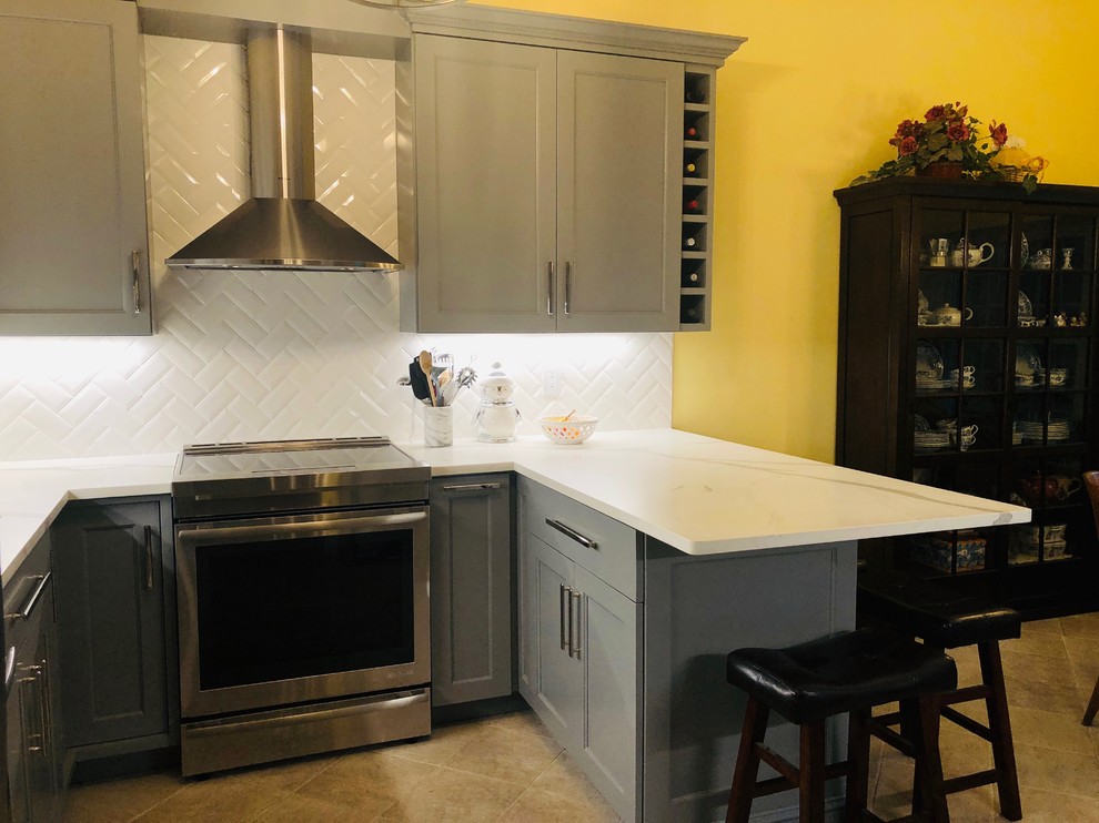 This is an example of a small modern u-shaped kitchen pantry in Boston with a single-bowl sink, shaker cabinets, grey cabinets, marble benchtops, white splashback, subway tile splashback, stainless steel appliances, ceramic floors, a peninsula, beige floor and white benchtop.