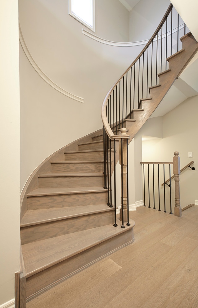 Large contemporary wood curved staircase in Other with wood risers and metal railing.