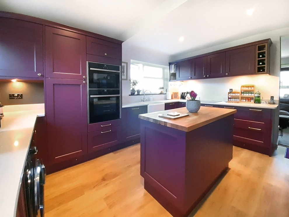 Photo of a small traditional u-shaped enclosed kitchen in Cornwall with shaker cabinets, red cabinets, quartz worktops, an island and white worktops.