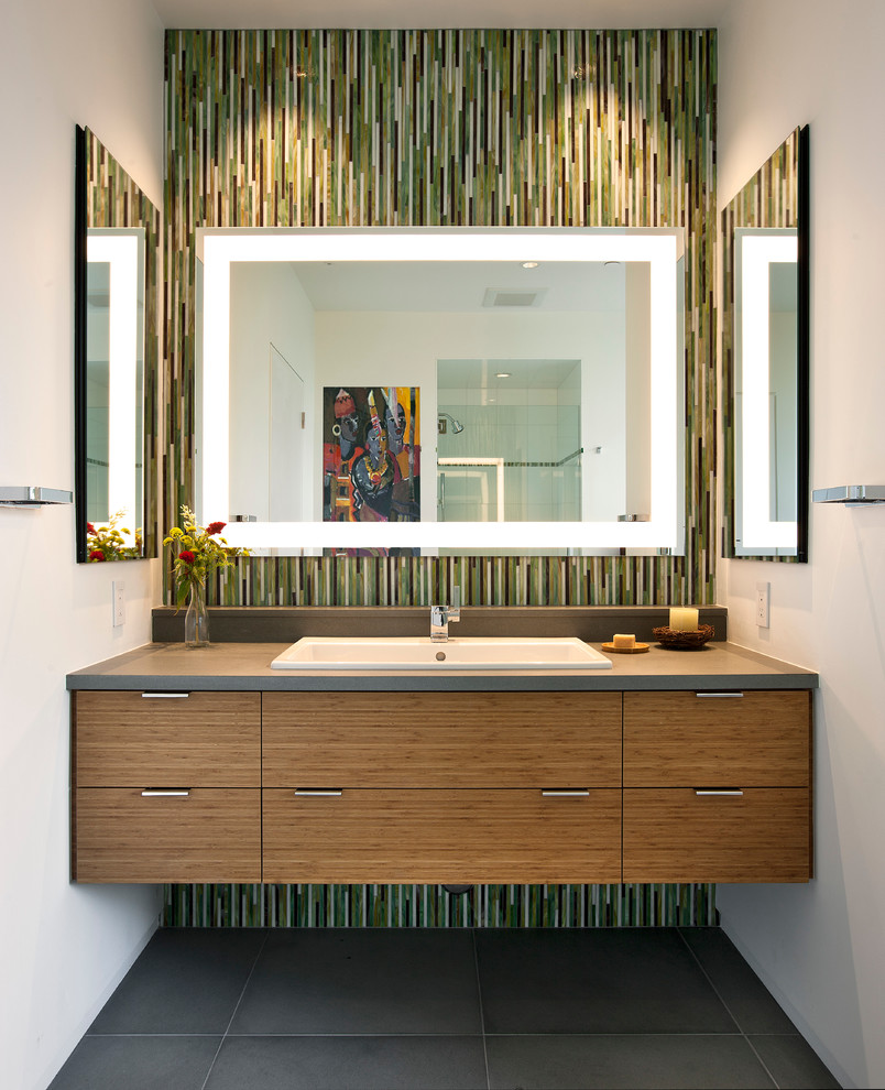 Inspiration for a mid-sized contemporary bathroom in Santa Barbara with a drop-in tub, black tile, green tile, white tile, yellow tile, matchstick tile, white walls, cement tiles, flat-panel cabinets, light wood cabinets, an alcove shower, a drop-in sink, solid surface benchtops, grey floor, a hinged shower door and grey benchtops.