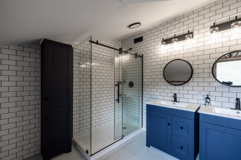 Large country master bathroom in Ottawa with shaker cabinets, blue cabinets, a freestanding tub, a corner shower, a two-piece toilet, white tile, subway tile, grey walls, painted wood floors, an integrated sink, solid surface benchtops, grey floor, a sliding shower screen, white benchtops, a single vanity, a freestanding vanity and vaulted.