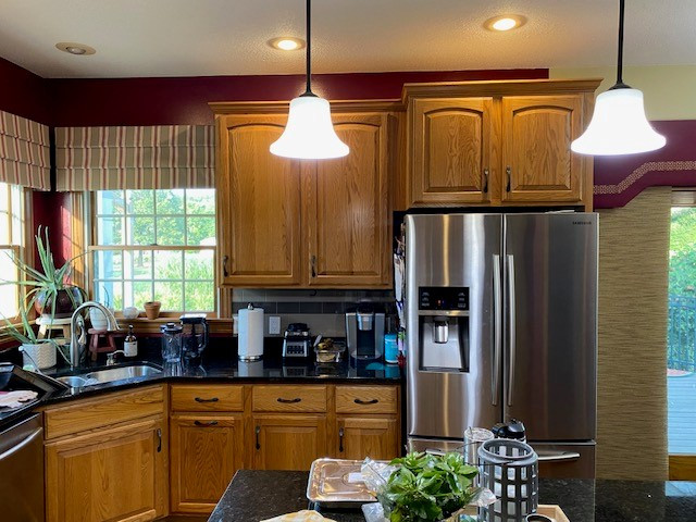 Large transitional l-shaped laminate floor and brown floor open concept kitchen photo with an undermount sink, flat-panel cabinets, white cabinets, quartz countertops, white backsplash, ceramic backsplash, stainless steel appliances, an island and white countertops