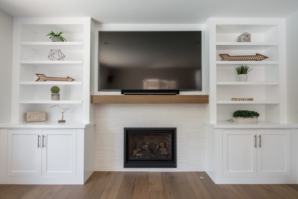 Photo of a mid-sized contemporary open concept family room in San Francisco with a library, white walls, medium hardwood floors, a standard fireplace, a stone fireplace surround, a wall-mounted tv and brown floor.