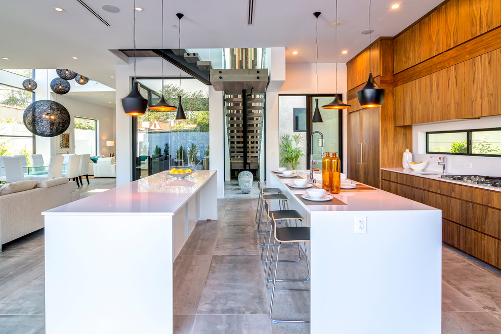 This is an example of a contemporary galley kitchen in Los Angeles with flat-panel cabinets, medium wood cabinets, panelled appliances and multiple islands.
