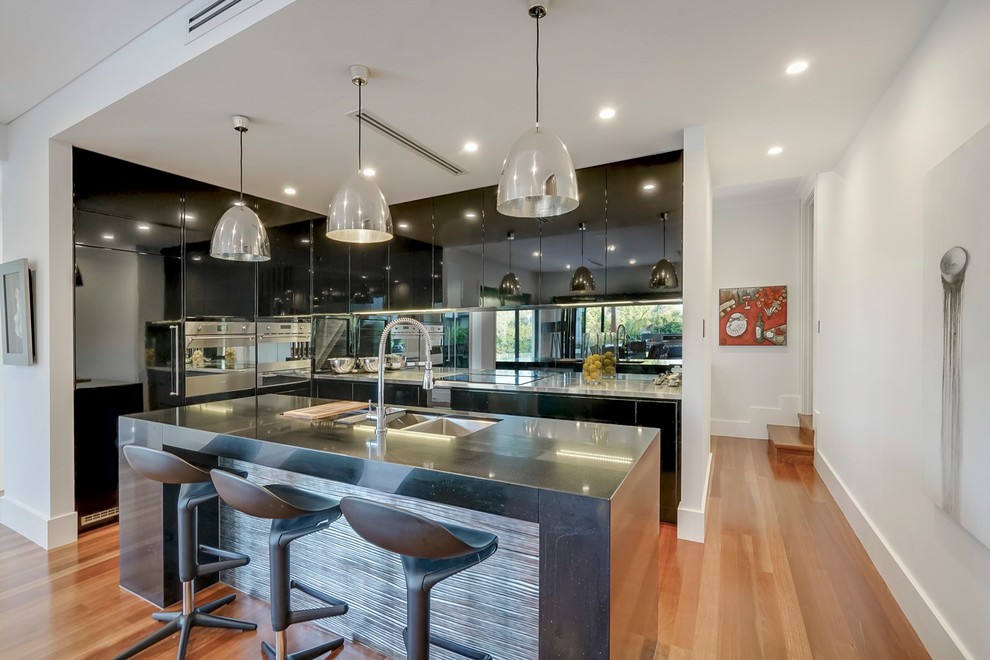 Inspiration for a large tropical open plan kitchen in Sydney with a double-bowl sink, black cabinets, stainless steel appliances and with island.