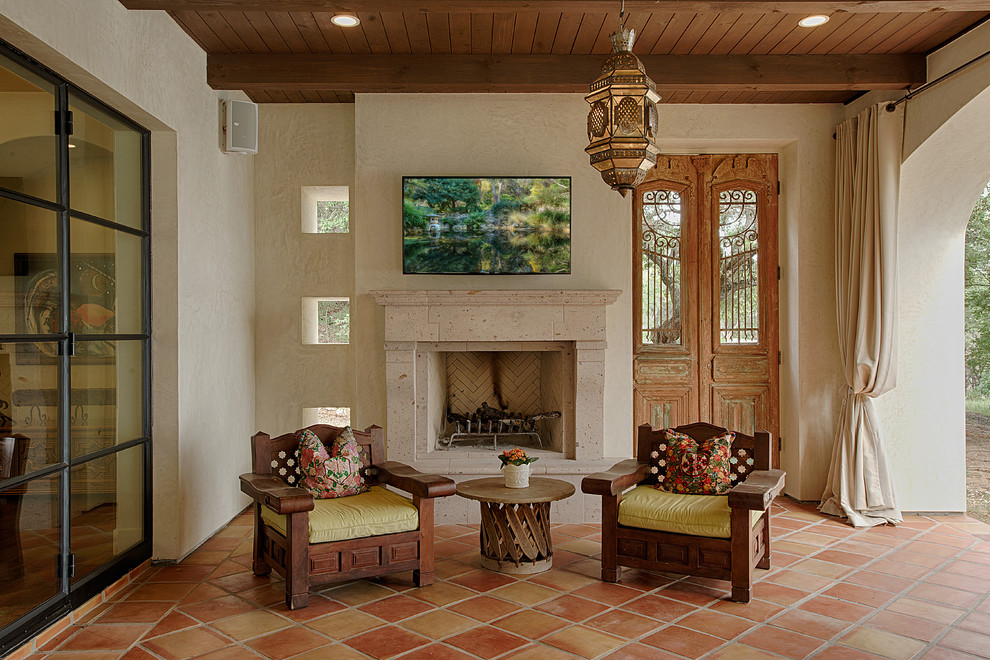 Design ideas for a mediterranean side yard patio in Austin with tile, a roof extension and with fireplace.