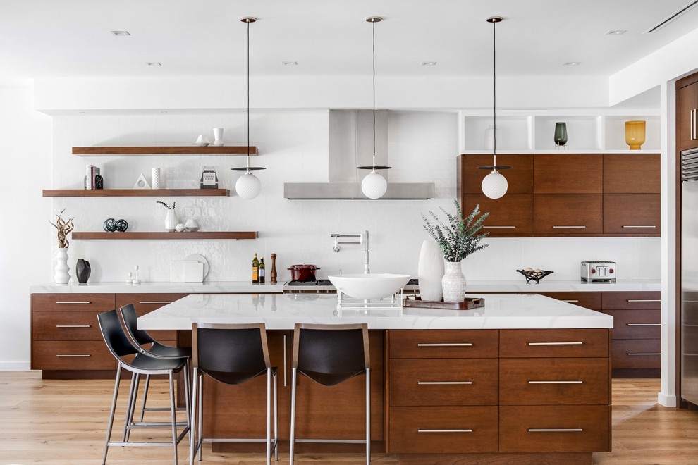 Photo of a contemporary galley kitchen in Los Angeles with flat-panel cabinets, medium wood cabinets, medium hardwood floors, with island, brown floor and white benchtop.
