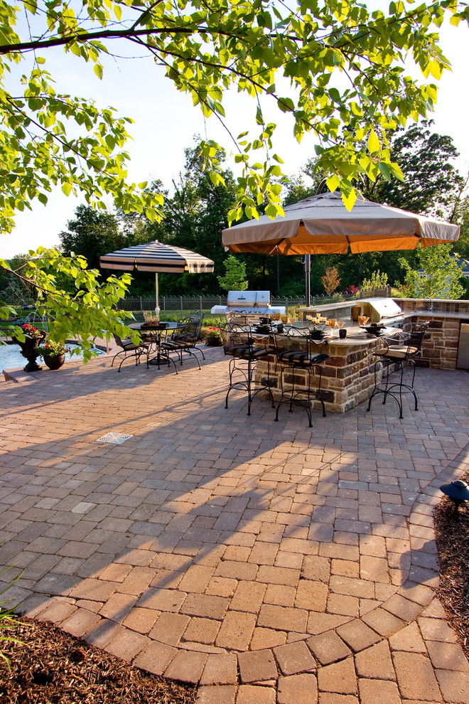 Photo of a large traditional backyard patio in Other with a water feature, natural stone pavers and an awning.