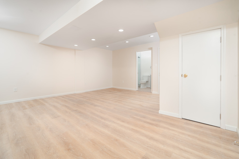 This is an example of a large traditional walk-out basement in DC Metro with beige walls, vinyl floors and brown floor.