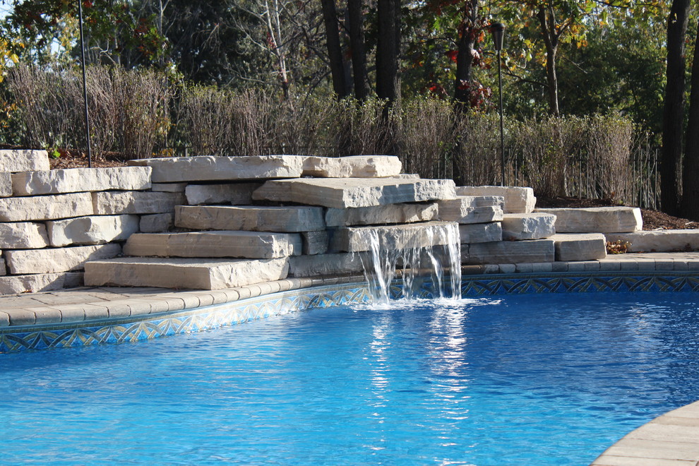Large transitional backyard custom-shaped natural pool in Chicago with a water feature and brick pavers.