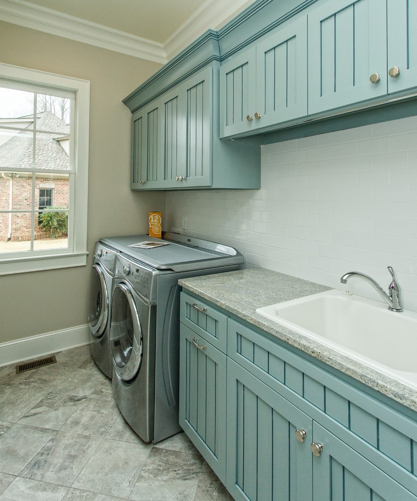 Mid-sized traditional single-wall dedicated laundry room in Other with a drop-in sink, recessed-panel cabinets, blue cabinets, granite benchtops, beige walls, porcelain floors, a side-by-side washer and dryer and grey benchtop.