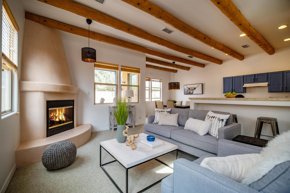 Mid-sized open concept living room in Other with white walls, carpet, a corner fireplace, a plaster fireplace surround, no tv, green floor and exposed beam.