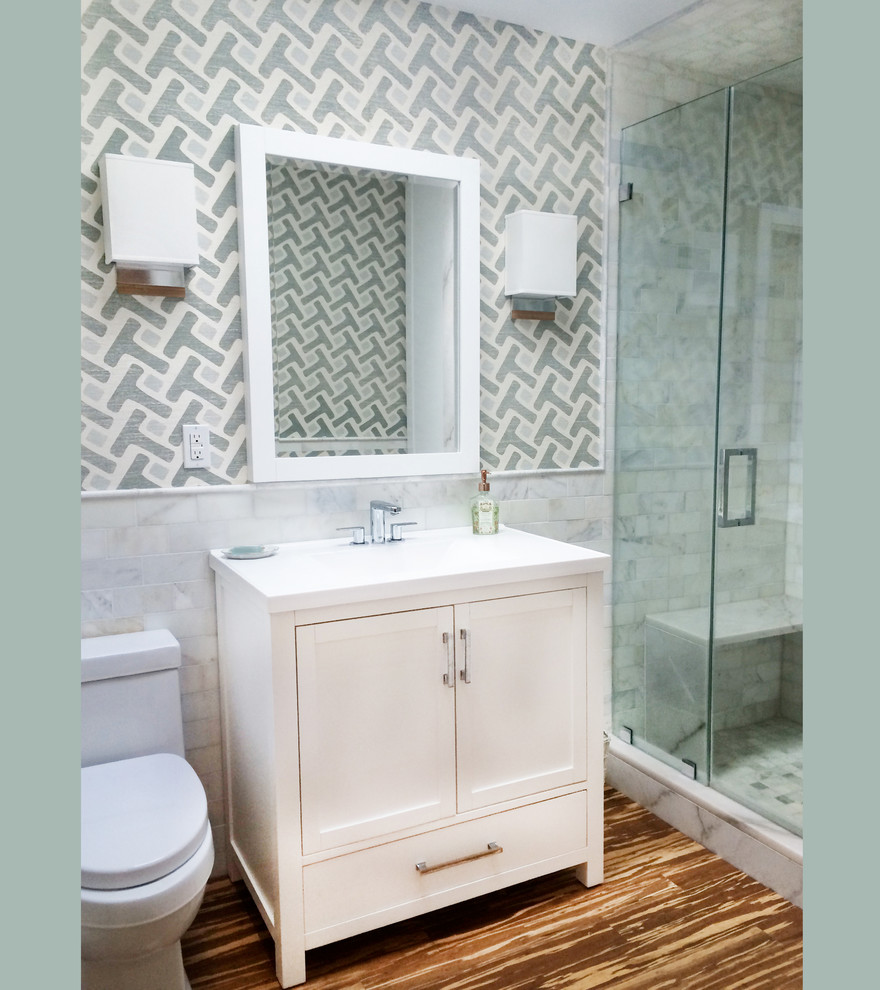 Photo of a small transitional 3/4 bathroom in New York with furniture-like cabinets, white cabinets, an alcove shower, gray tile, white tile, stone tile, multi-coloured walls, an integrated sink, solid surface benchtops, a hinged shower door and bamboo floors.