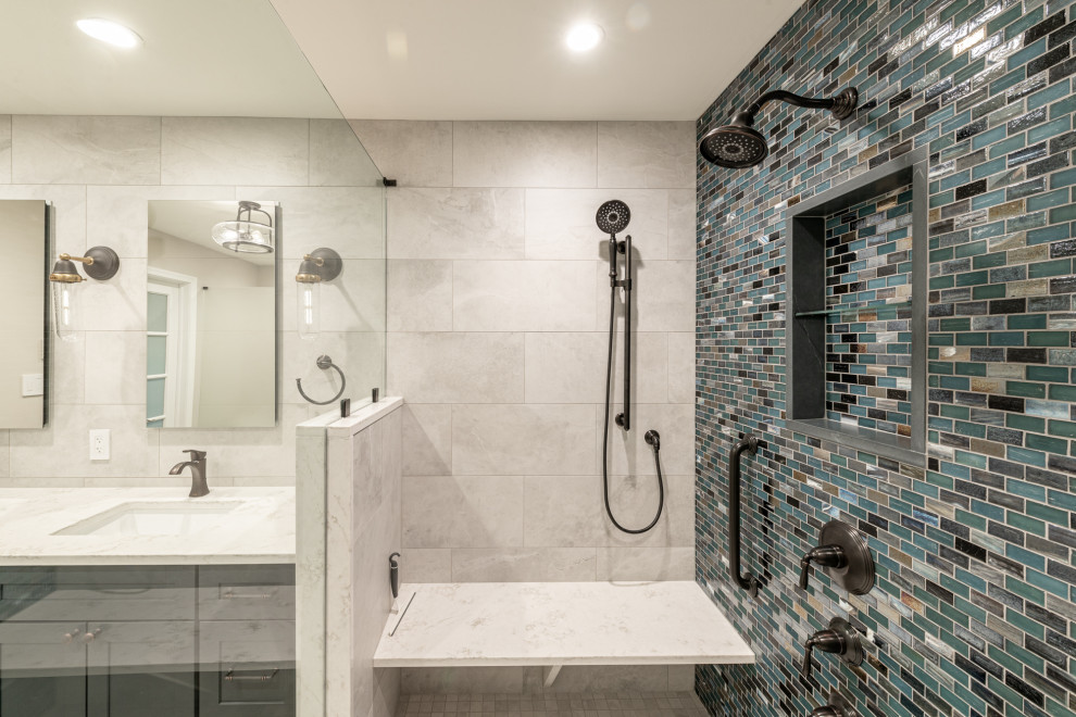 This is an example of a large transitional master bathroom in Philadelphia with shaker cabinets, blue cabinets, an open shower, a one-piece toilet, white tile, porcelain tile, white walls, wood-look tile, an undermount sink, quartzite benchtops, brown floor, a hinged shower door, white benchtops, a shower seat, a double vanity, a built-in vanity and wallpaper.