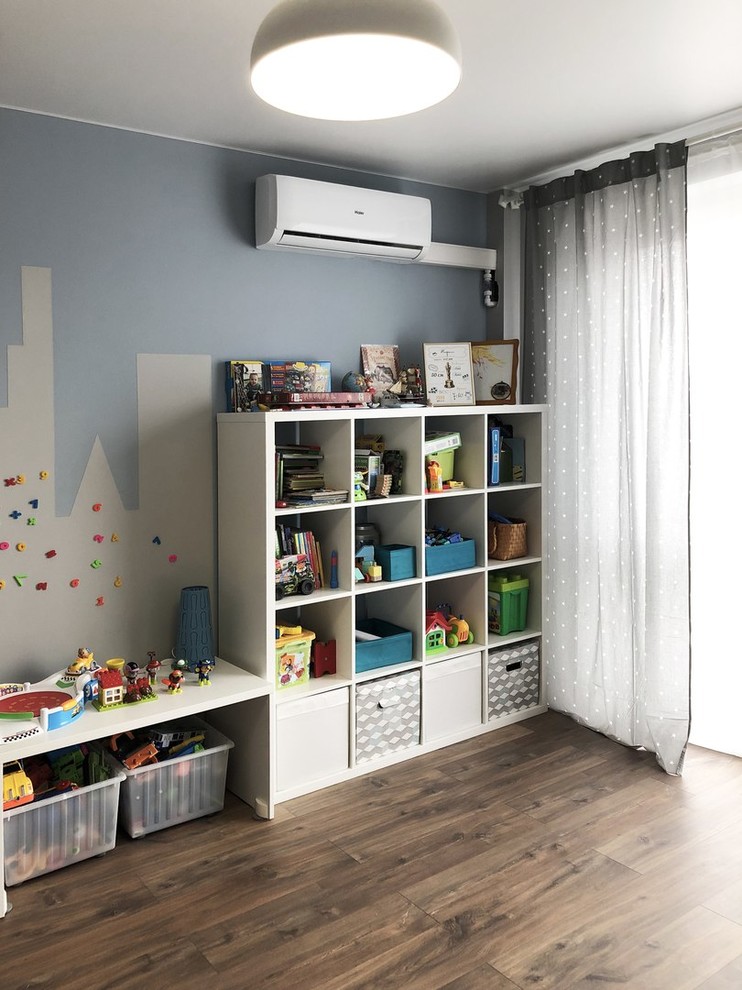This is an example of a mid-sized scandinavian gender-neutral kids' playroom for kids 4-10 years old in Moscow with blue walls, laminate floors and brown floor.