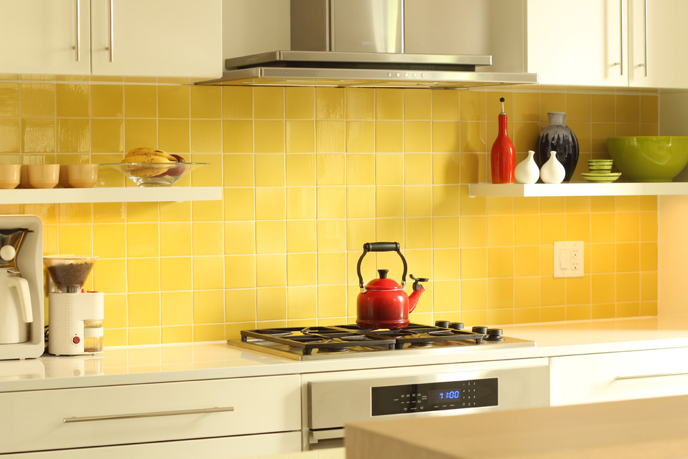 This is an example of a small modern single-wall open plan kitchen in Other with a double-bowl sink, flat-panel cabinets, white cabinets, quartz benchtops, yellow splashback, ceramic splashback, panelled appliances, concrete floors and with island.