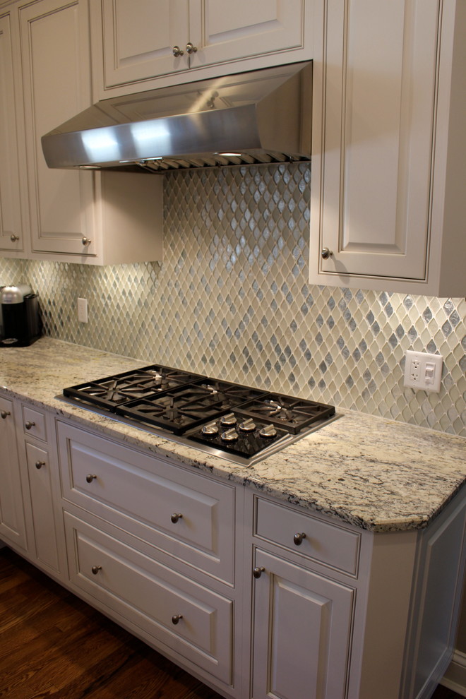 This is an example of a mid-sized modern l-shaped eat-in kitchen in Cincinnati with an undermount sink, raised-panel cabinets, white cabinets, granite benchtops, multi-coloured splashback, mosaic tile splashback, stainless steel appliances and with island.