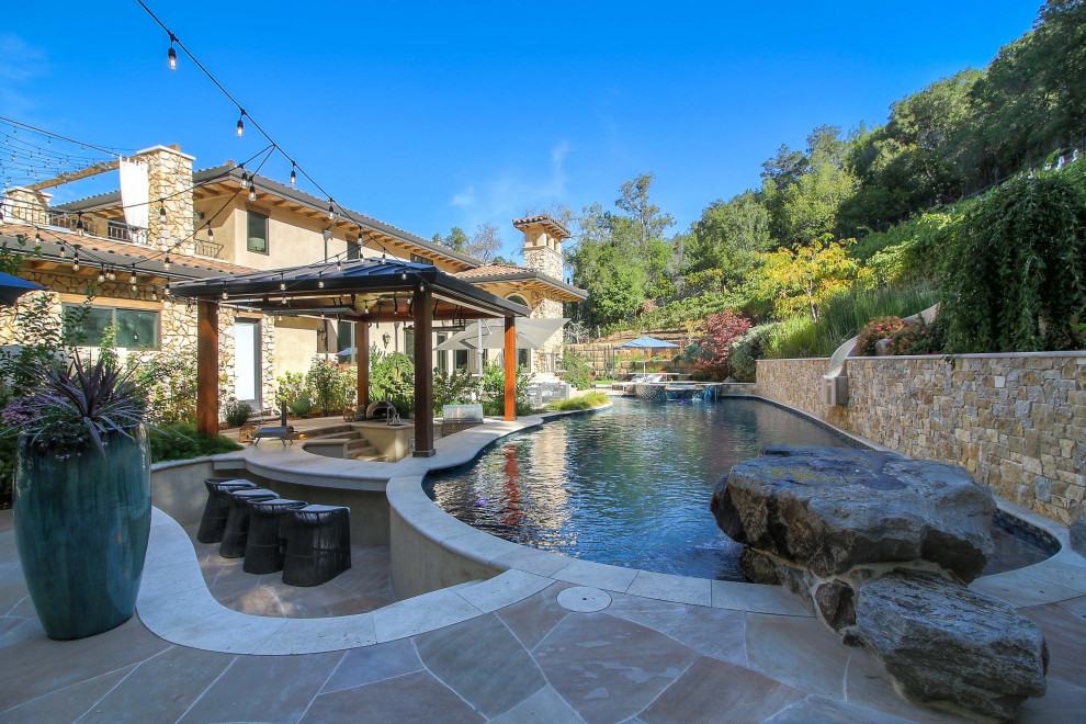 This is an example of a large mediterranean back patio in San Francisco with natural stone paving.