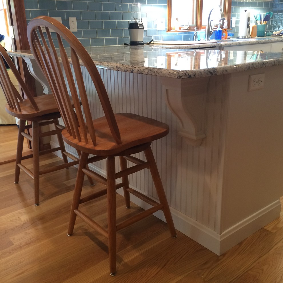 Example of a transitional u-shaped medium tone wood floor eat-in kitchen design in Boston with an undermount sink, raised-panel cabinets, white cabinets, granite countertops, blue backsplash, glass tile backsplash, stainless steel appliances and an island