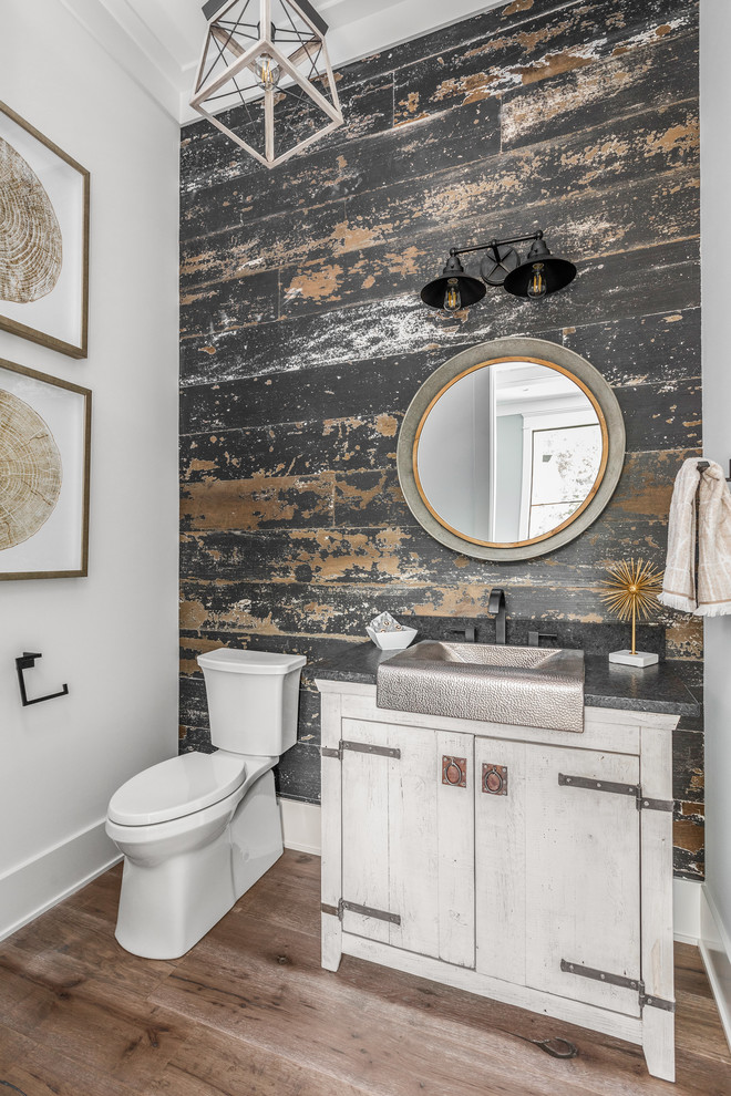 Inspiration for a large country powder room in Indianapolis with recessed-panel cabinets, white cabinets, a one-piece toilet, white tile, ceramic tile, white walls, medium hardwood floors, a drop-in sink, granite benchtops, multi-coloured floor and black benchtops.