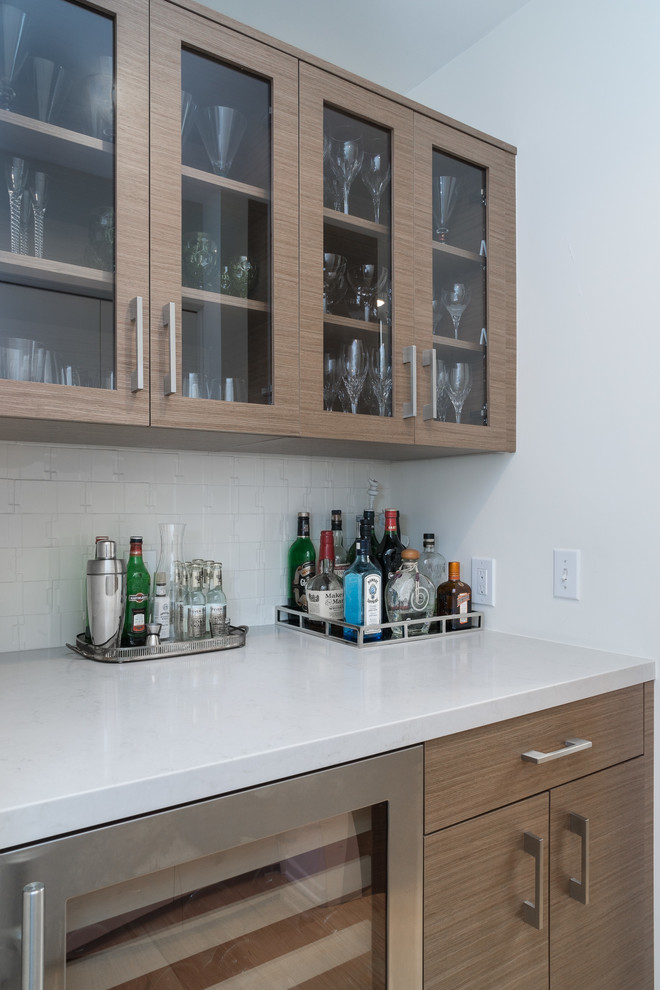 Design ideas for a small midcentury single-wall home bar in Los Angeles with an undermount sink, flat-panel cabinets, medium wood cabinets, quartz benchtops, white splashback, ceramic splashback and light hardwood floors.