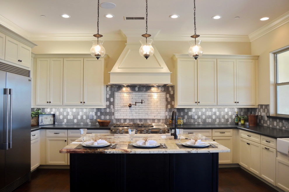 Example of a mid-sized transitional u-shaped medium tone wood floor enclosed kitchen design with a farmhouse sink, recessed-panel cabinets, white cabinets, solid surface countertops, gray backsplash, ceramic backsplash, stainless steel appliances and an island