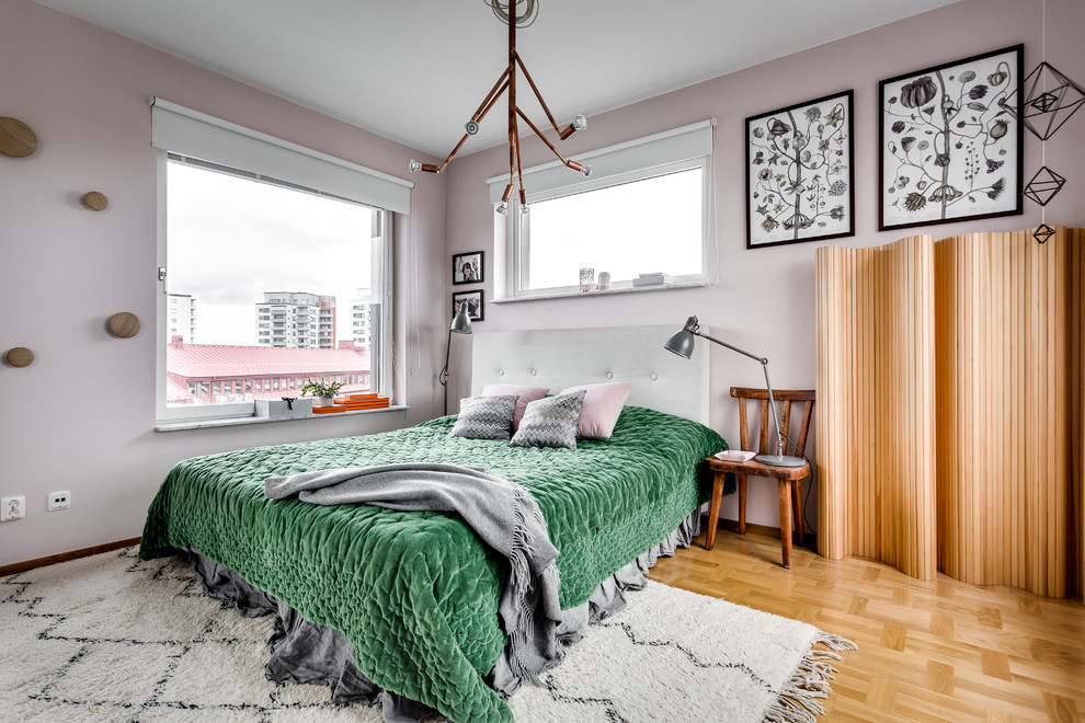 Photo of a mid-sized contemporary master bedroom in Stockholm with pink walls and light hardwood floors.