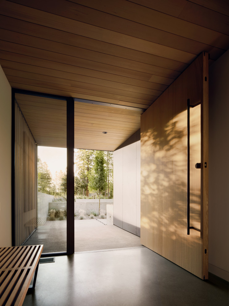 Minimalist concrete floor, gray floor and wood ceiling pivot front door photo with beige walls and a medium wood front door