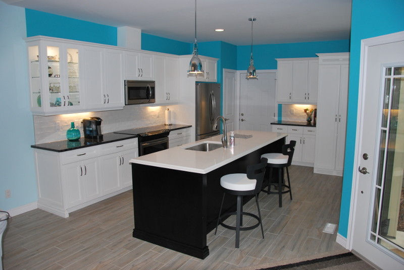 This is an example of a mid-sized transitional l-shaped kitchen in Toronto with with island, an undermount sink, stainless steel appliances, porcelain floors, beige floor, recessed-panel cabinets, white cabinets, granite benchtops, white splashback, subway tile splashback and black benchtop.