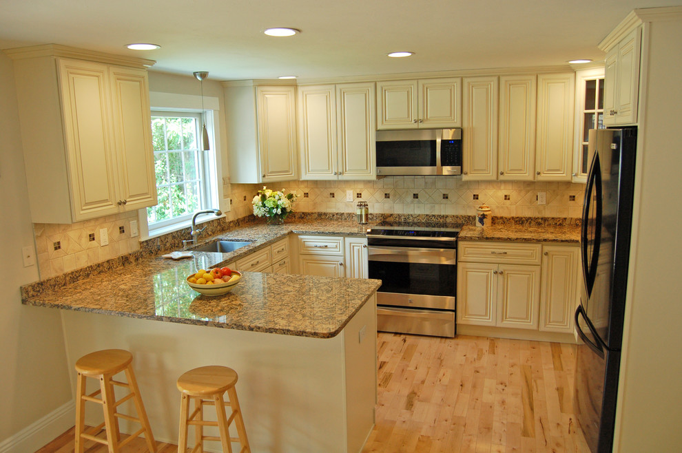 Inspiration for a traditional u-shaped eat-in kitchen in Boston with an undermount sink, raised-panel cabinets, beige cabinets, granite benchtops, beige splashback, ceramic splashback, stainless steel appliances, light hardwood floors and a peninsula.