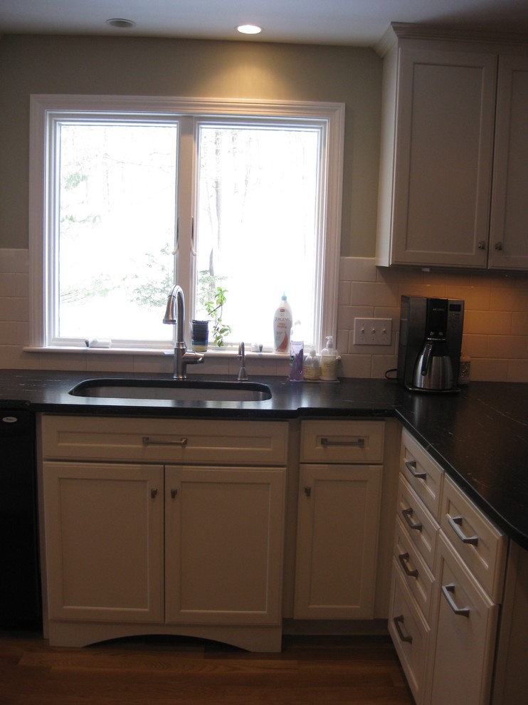 Eat-in kitchen - transitional l-shaped medium tone wood floor eat-in kitchen idea in Boston with an undermount sink, shaker cabinets, white cabinets, quartz countertops, white backsplash, ceramic backsplash, stainless steel appliances, an island and black countertops
