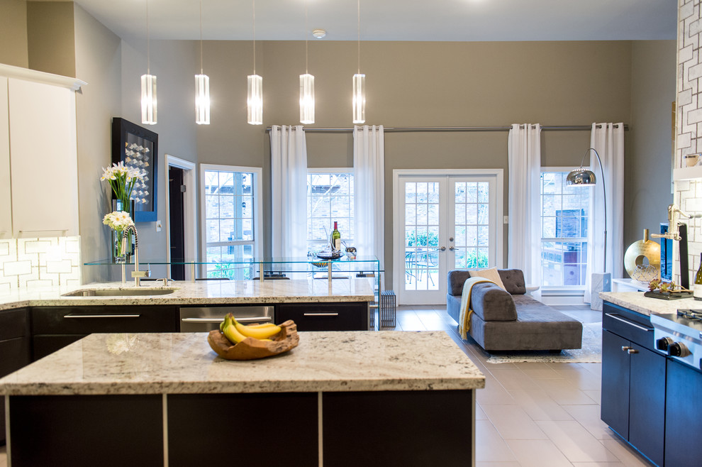 Photo of a mid-sized contemporary u-shaped eat-in kitchen in New Orleans with an integrated sink, flat-panel cabinets, black cabinets, granite benchtops, multi-coloured splashback, stainless steel appliances, limestone floors and with island.
