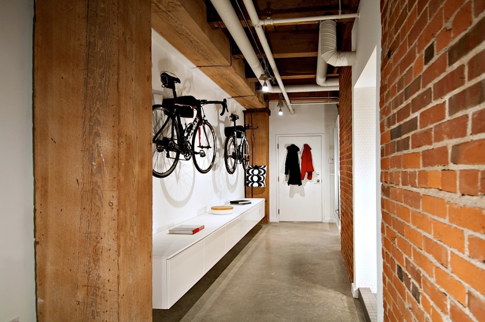 This is an example of a small eclectic hallway in Other with white walls and concrete floors.