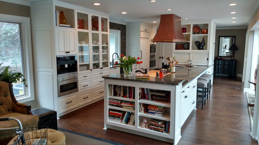 Large country galley eat-in kitchen in Minneapolis with an undermount sink, raised-panel cabinets, white cabinets, granite benchtops, brown splashback, stone slab splashback, white appliances, dark hardwood floors and with island.