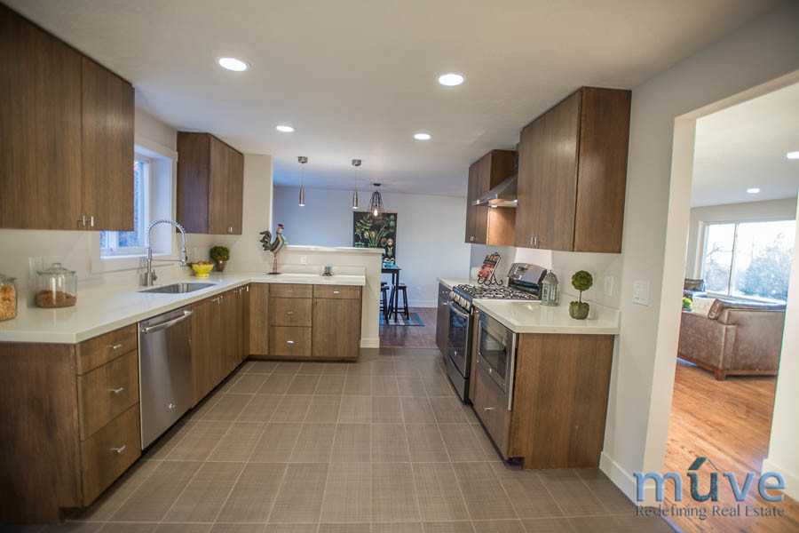 Photo of a midcentury u-shaped eat-in kitchen in Salt Lake City with an undermount sink, flat-panel cabinets, dark wood cabinets, marble benchtops and stainless steel appliances.