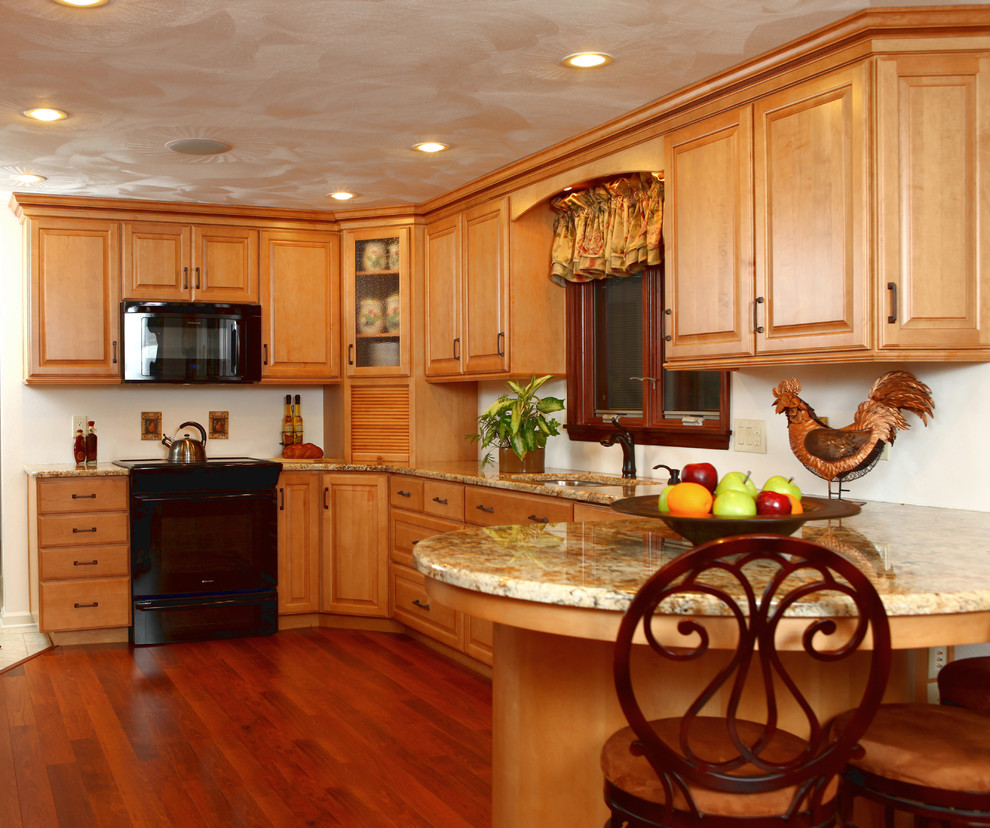 Mid-sized transitional l-shaped medium tone wood floor eat-in kitchen photo in New York with an undermount sink, raised-panel cabinets, medium tone wood cabinets, granite countertops and black appliances