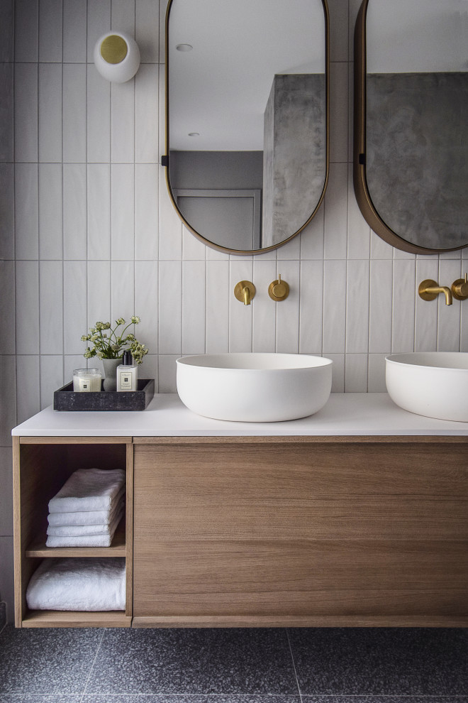 Exemple d'une salle de bain principale tendance en bois brun de taille moyenne avec une douche à l'italienne, un carrelage blanc, des carreaux de porcelaine, un mur blanc, un lavabo posé, un plan de toilette en surface solide, un plan de toilette blanc, meuble double vasque et meuble-lavabo encastré.