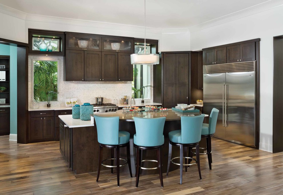 Photo of a mid-sized contemporary l-shaped open plan kitchen in Orlando with a farmhouse sink, shaker cabinets, dark wood cabinets, zinc benchtops, white splashback, porcelain splashback, stainless steel appliances, dark hardwood floors and with island.