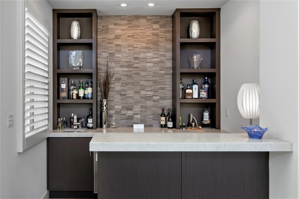 Inspiration for a mid-sized contemporary galley wet bar in Los Angeles with an undermount sink, flat-panel cabinets, dark wood cabinets, quartz benchtops, beige splashback, limestone splashback, limestone floors, beige floor and white benchtop.