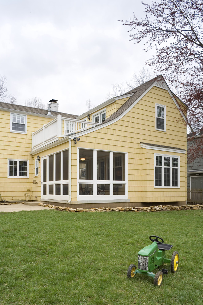 This is an example of a small traditional two-storey yellow exterior in Kansas City with wood siding.