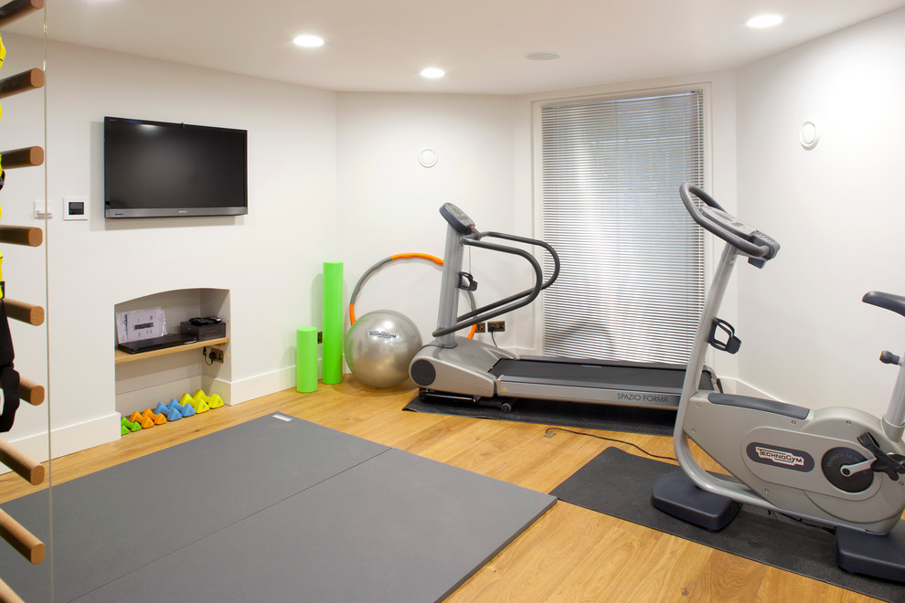 Photo of a contemporary home gym in Kent with white walls and light hardwood floors.